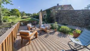 a wooden deck with chairs and furniture on it at Le Mas Bellane in Salettes