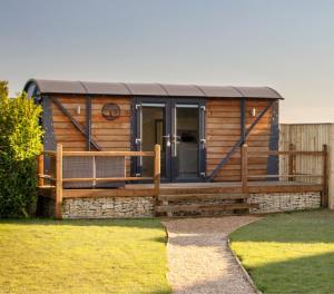 a log cabin with a porch and a wooden fence at Yew Lodge - Shepherd's Hut Railway Carriage with "Hot Tub" - Sleeps 4 - Escape Completely! in Boston