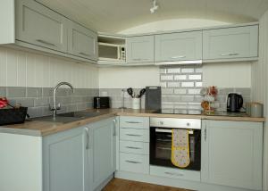 a kitchen with white cabinets and a sink and an oven at Yew Lodge - Shepherd's Hut Railway Carriage with "Hot Tub" - Sleeps 4 - Escape Completely! in Boston