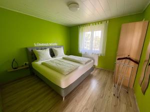 a green bedroom with a bed and a window at Gästehaus Durst in Rust