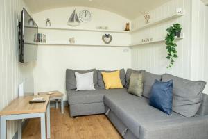 a living room with a gray couch with colorful pillows at Yew Lodge - Shepherd's Hut Railway Carriage with "Hot Tub" - Sleeps 4 - Escape Completely! in Boston