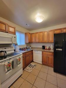 a kitchen with wooden cabinets and a black refrigerator at Lovely welcoming 3 bedroom house 