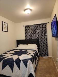 a bedroom with a black and white bed and a window at Lovely welcoming 3 bedroom house 