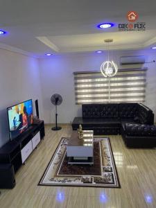 a living room with a black couch and a tv at Dex & Flex Apartments in Ibadan