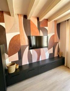 a living room with a television and a wall with a mural at Tres bel appartement le Concordance in Mulhouse