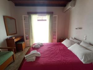 1 dormitorio con 1 cama grande de color rojo y ventana en Villa Aliki, en Ágios Stéfanos