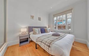 a white bedroom with a bed and a window at GARDEN Flat in Posh MEWS in London