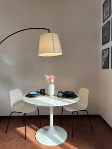 Avdkapartment في ميلانو: طاولة بيضاء مع كرسيين ومصباح