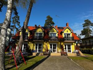 a large yellow house with a red roof at Dom pod Sosnami in Pobierowo