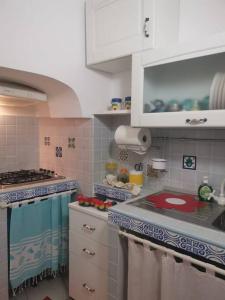 una cucina con armadi bianchi e piano di lavoro rosso di Casa Centro storico Gallipoli a Gallipoli