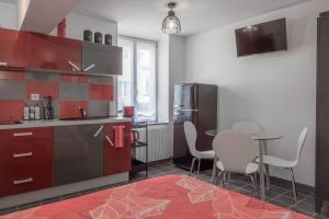 uma cozinha com armários vermelhos, uma mesa e cadeiras em Studio Le Ligérien em Saint-Denis-de lʼHôtel