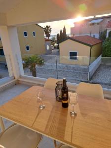 维尔Mala Smokva Apartments Vir Prezida的木桌旁的一瓶葡萄酒,带两杯