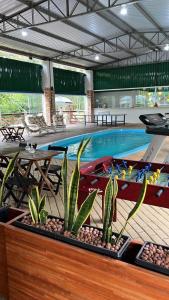 una piscina con una mesa y plantas frente a ella en HOTEL Recanto dos Bambus em PALMEIRINHA, en Guarapuava