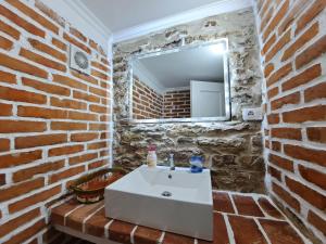 uma casa de banho com um lavatório branco e uma parede de tijolos em "Villa 70" Guesthouse em Gjirokastër