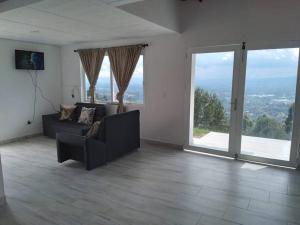 a living room with a couch and large windows at El Mirador de LucyMelia in Guarne