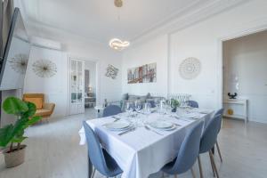 a white dining room with a table and blue chairs at PENTHOUSE deluxe GRANVIA, by MONARO in Madrid