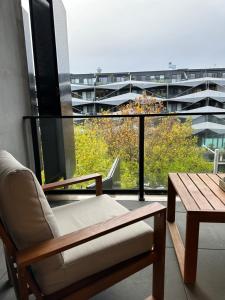 Cette chambre comprend une chaise, une table et une grande fenêtre. dans l'établissement Palko - Luxury In the City, à Canberra