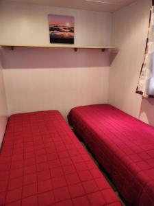 duas camas num quarto com lençóis vermelhos em A casinha do João em Alcobaça