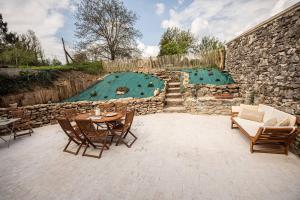 a patio with a table and chairs next to a stone wall at Le clos des voisins in Verneuil