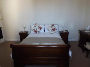 a bedroom with a wooden bed with two night stands at Lornebank Homestay in Lauder