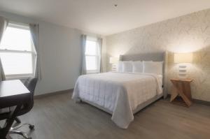 1 dormitorio con 1 cama blanca grande y escritorio en Westborough Inn, en Westborough