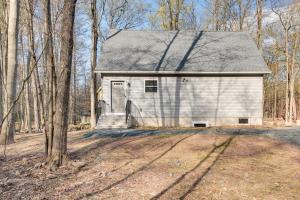 a white house with a garage in the woods at Pocono Lake Vacation Rental Community Amenities! in Pocono Lake