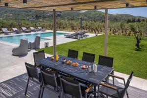 a dining table and chairs on a patio next to a pool at Demar Exclusive Villa in Plakias