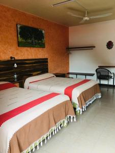 two beds in a room with orange walls at El Rincón de Doña Bety in Oaxaca City