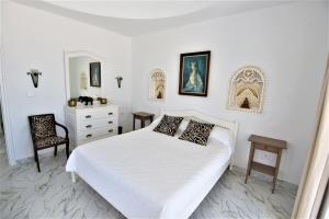 a white bedroom with a bed and a chair at VILLA KIKA ZARZIS, LOCATION CHAMBRES D'HÔTES en TUNISIE in Zarzis