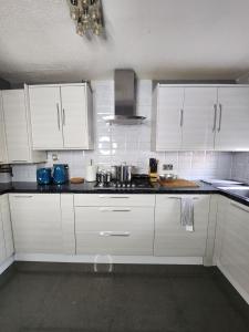 a kitchen with white cabinets and a stove top oven at Home away from Home in Woolwich