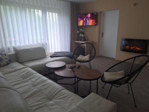 a living room with a couch and chairs and a tv at Apartmani Bosna Visoko in Visoko