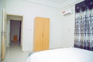 a bedroom with a white bed and a wooden cabinet at SeneGambia Beach Apartments in Bijilo