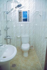 a bathroom with a white toilet and a sink at SeneGambia Beach Apartments in Bijilo