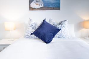 Una cama blanca con una almohada azul. en Christchurch Entertainment Hub 2 bed 2 bath w carpark, en Christchurch