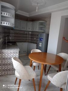 a kitchen with a wooden table and white chairs at Galia in Rafrāf