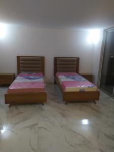 two twin beds in a room with a tv at Galia in Rafrāf