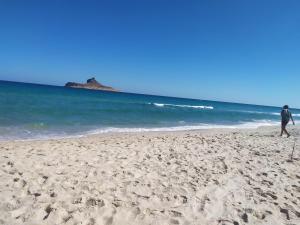 a person walking on a sandy beach near the ocean at Galia in Rafrāf