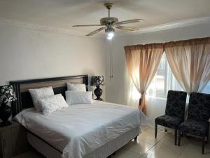 a bedroom with a bed with a ceiling fan and two chairs at AGASTEV GUESTHOUSE in Springs