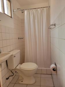 La salle de bains blanche est pourvue d'une douche et de toilettes. dans l'établissement Inka Roots Hostel, à Arequipa