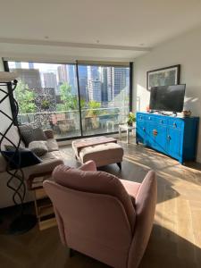 een woonkamer met een bank en stoelen en een tv bij Spacious 2 bed apartment, great location in Melbourne