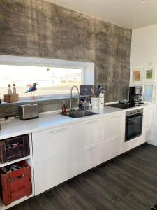 uma cozinha com armários brancos, um lavatório e uma janela em Melar Guesthouse em Kópasker