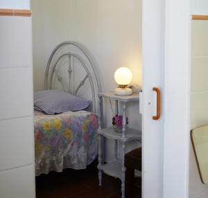 a bedroom with a bed and a table with a lamp at Casinha Robusto 