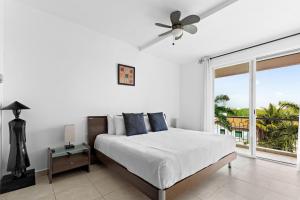 a white bedroom with a bed and a large window at 4 BR apartment, 8 guests in Cancún