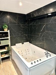 uma banheira na casa de banho com uma parede preta em Evasion dépaysante Canal du Midi * Terrasse & SPA em Castelnaudary