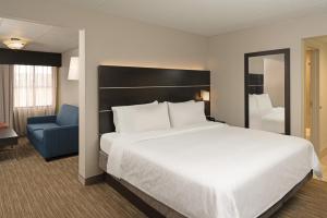 a bedroom with a large bed and a blue chair at Holiday Inn Express Rochester - Greece, an IHG Hotel in Rochester