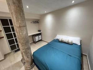 1 dormitorio con 1 cama azul junto a una palmera en Departamento Barrio de Santiago en Mérida