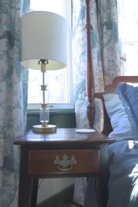 a table with a lamp on it next to a bed at Charming Victorian Home In Historic District in Newburgh