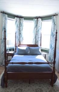 a bedroom with a bed with blue curtains and windows at Charming Victorian Home In Historic District in Newburgh