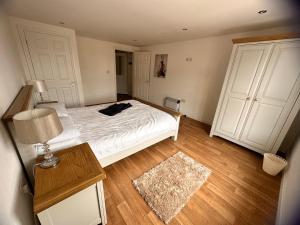 a bedroom with a white bed with a lamp and a rug at Joe Kelly Buildings A in Withernsea