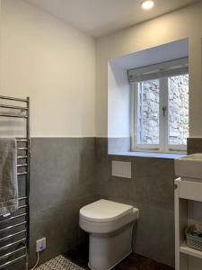 a bathroom with a toilet and a window at The Vottage - 3 bed cottage in Plymouth
